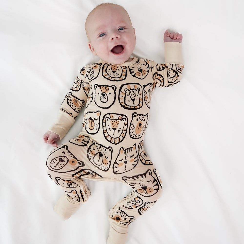 Child laying on a bed wearing a Lions, Tigers, and Bears crescent zippy