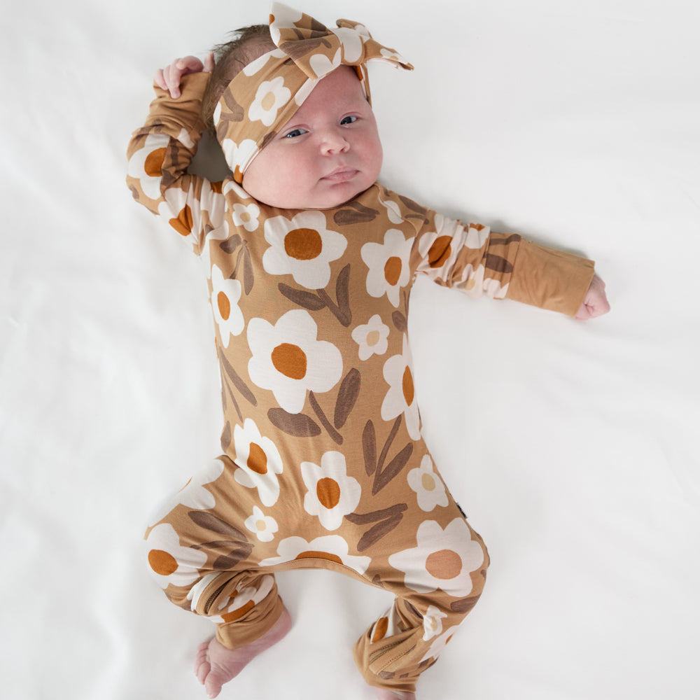 image of a child laying on a bed wearing a Daisy Daydream crescent zippy and matching luxe bow headband 