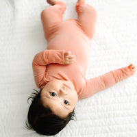 Alternate image of a child laying on a bed wearing a Peach Zippy