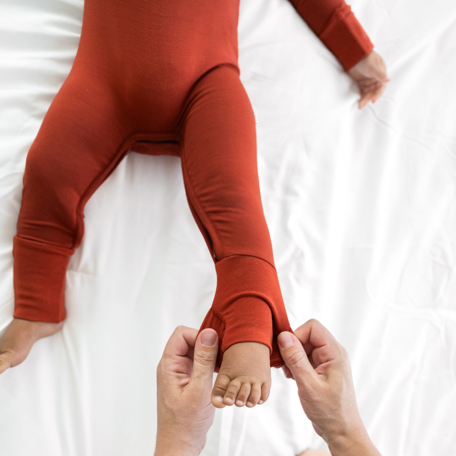 Close up image of the zipper on a Cozy Rust crescent zippy. Child's mother is demonstrating folding over the foot cuff