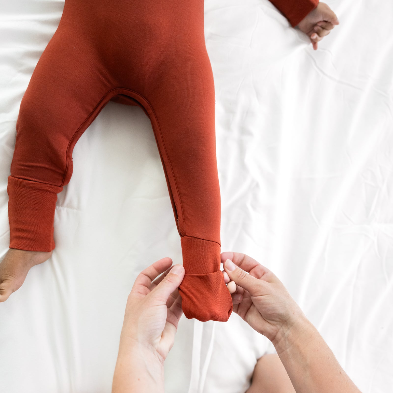 Close up image of the zipper on a Cozy Rust crescent zippy. Child's mother is showing the folded over foot cuff