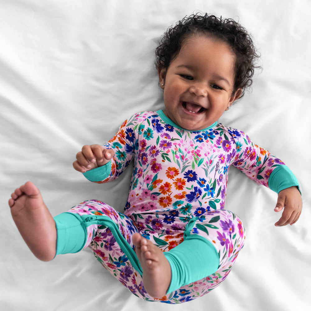 Child laying on a bed wearing a Sweet Pea Floral crescent zippy