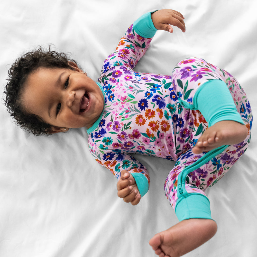 Alternate image of a child laying on a bed wearing a Sweet Pea Floral crescent zippy