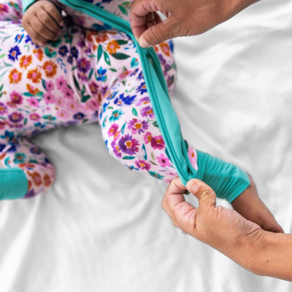 Close up image of a mother zipping the zipper on a Sweet Pea Floral crescent zippy