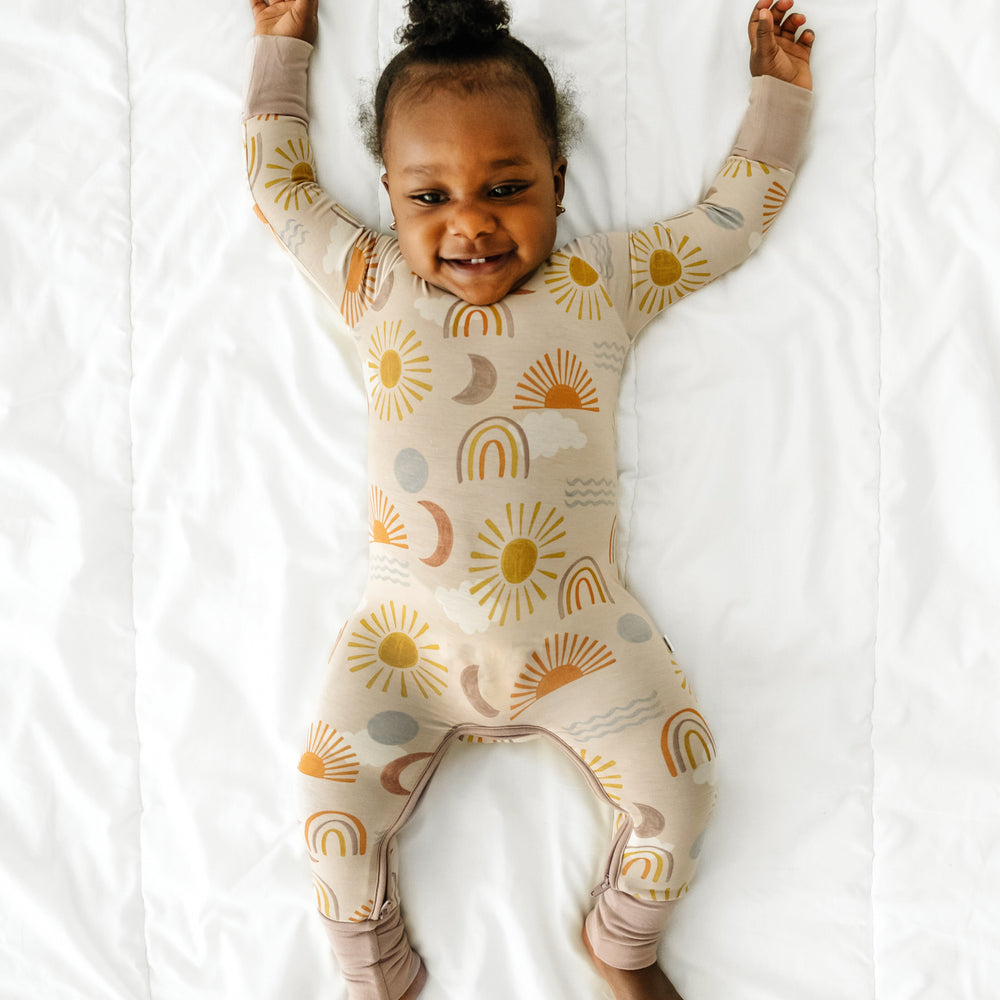 Child stretching on a bed wearing a Desert Sunrise crescent zippy
