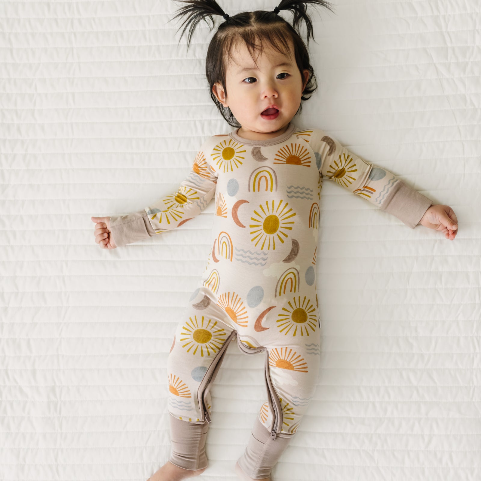 Child laying on a bed wearing a Desert Sunrise Crescent zippy