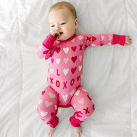 Child laying on a bed wearing a Pink XOXO crescent zippy