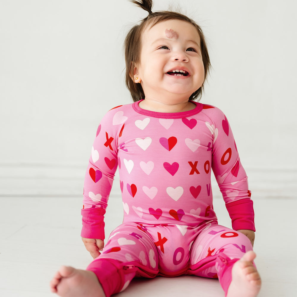 Click to see full screen - image of child sitting in a Pink XOXO crescent zippy