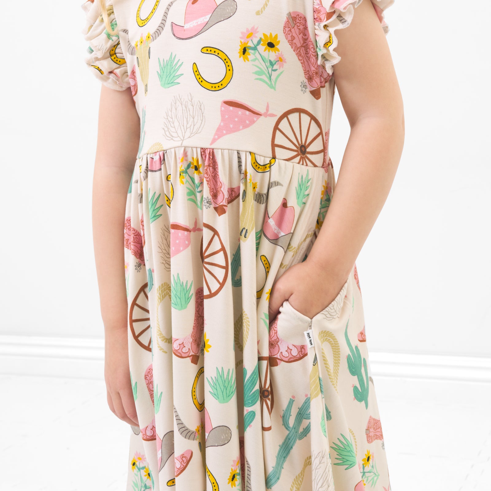 Close up image of a child posing wearing a Pink Ready to Rodeo twirl dress detailing the skirt pockets