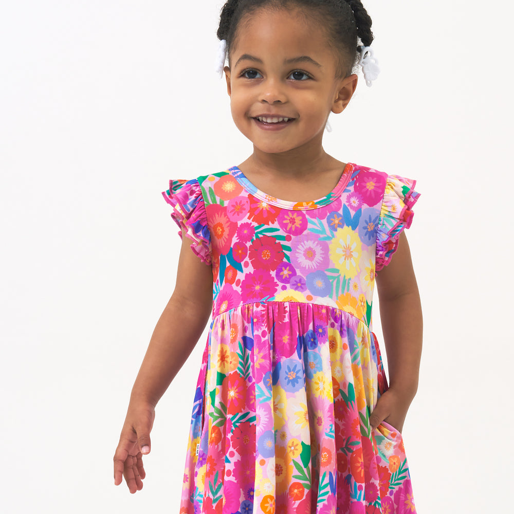 Close up image of a child wearing a Rainbow Blooms flutter twirl dress