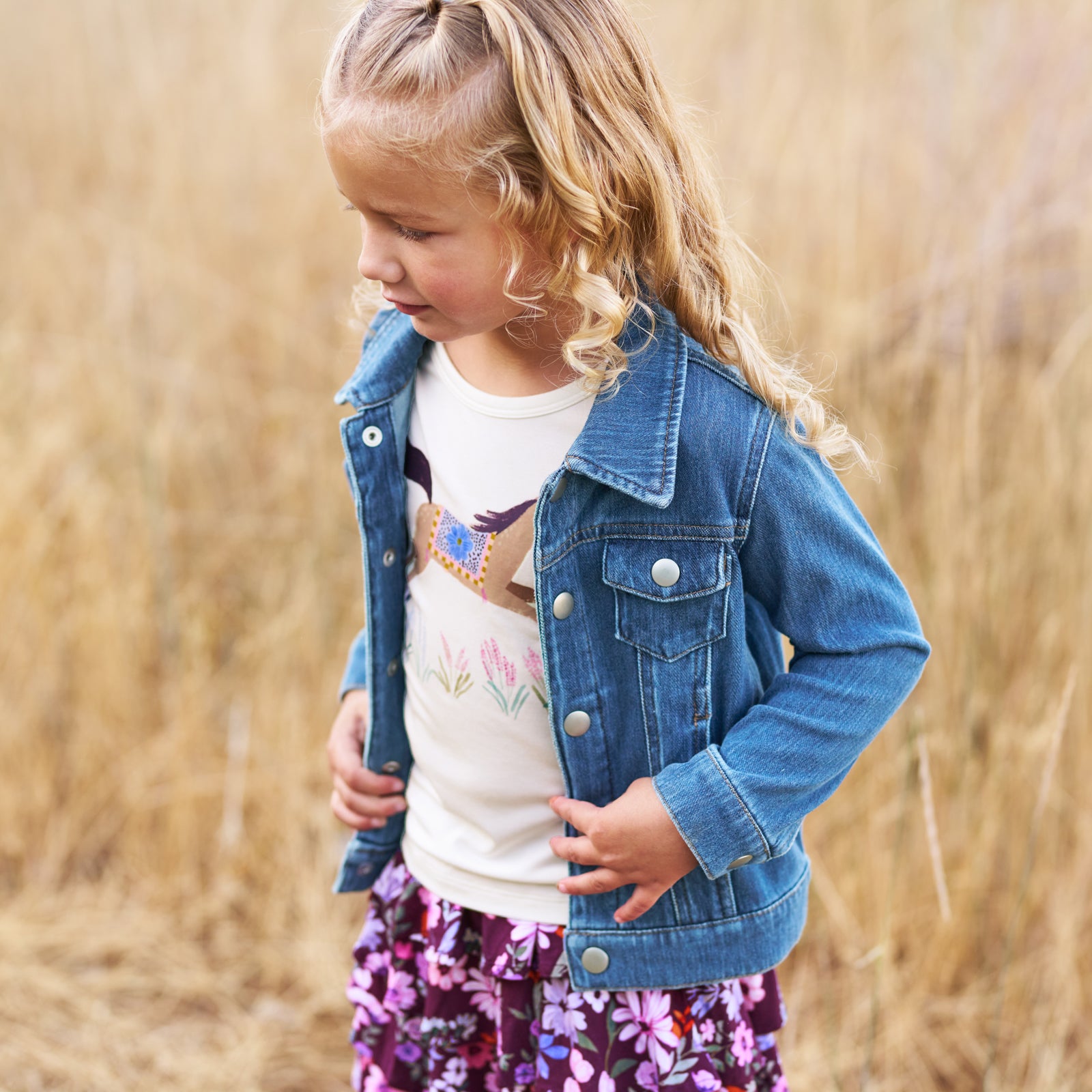 Girl outdoors wearing the Wildflower Ride Puff Sleeve Tee, Midwash Blue Denim Trucker Jacket and Violet Meadow Skort