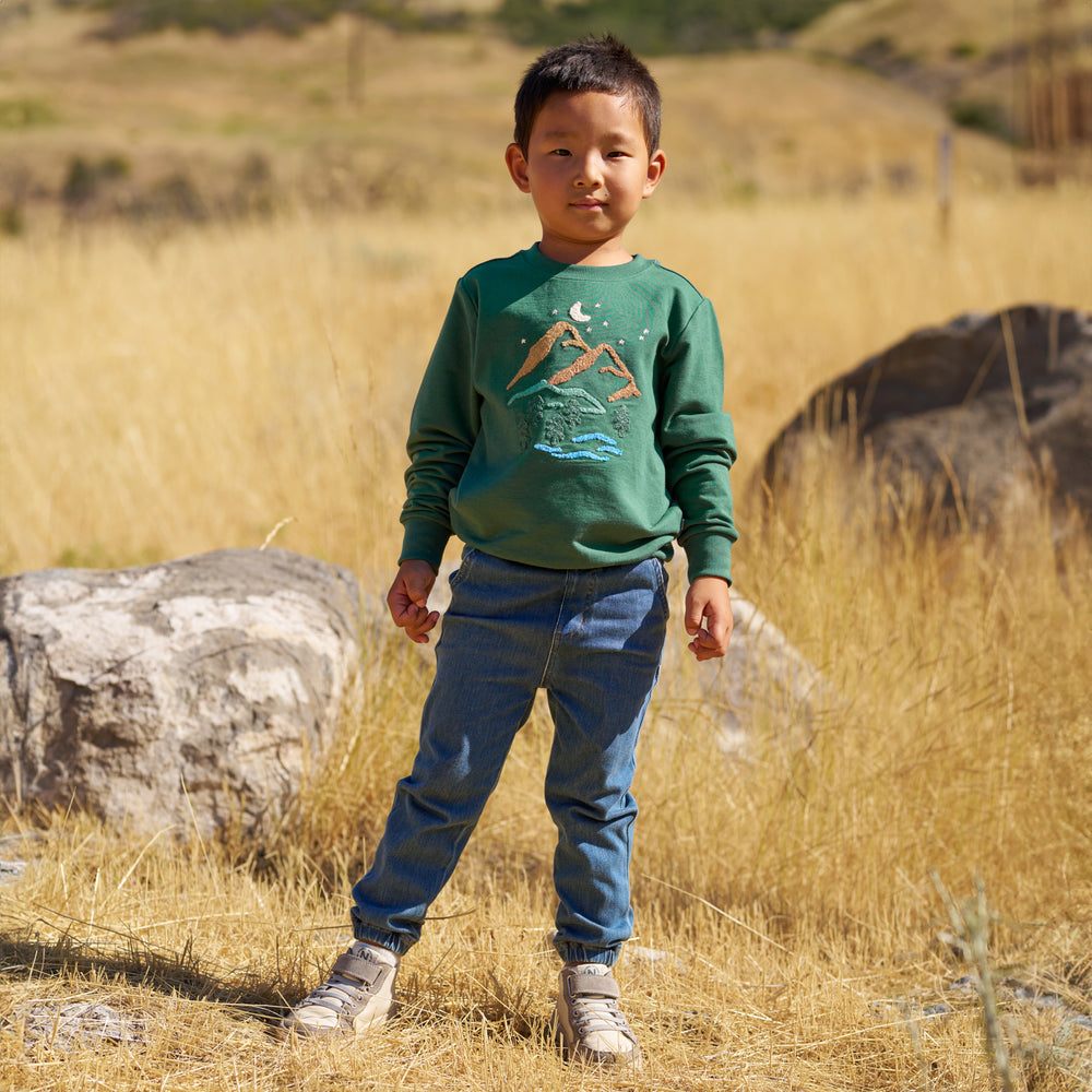 Boy outdoors while wearing the Heritage Green Graphic Crewneck and Midwash Denim Joggers