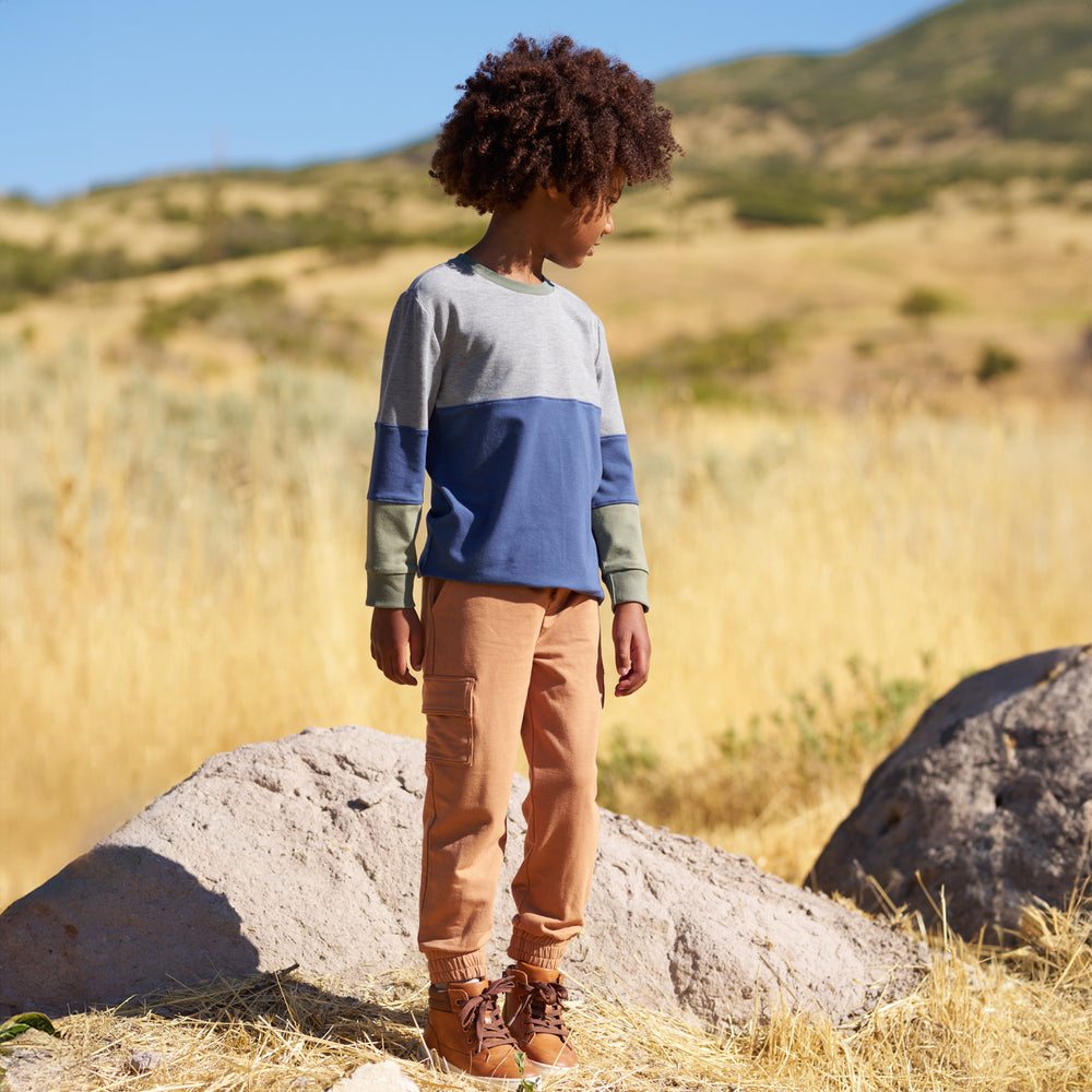 Boy outdoors wearing the Caramel Cargo Jogger and a colorblock crewneck 