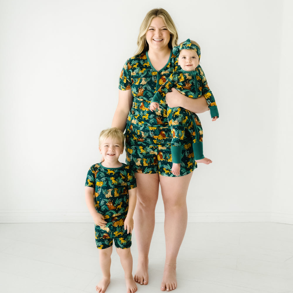 Mother and her two children sitting. Mom is wearing women's Disney Simba's Sky women's pajama shorts paired with a matching women's pajama top. Their children are wearing matching pjs in zippy and two piece styles