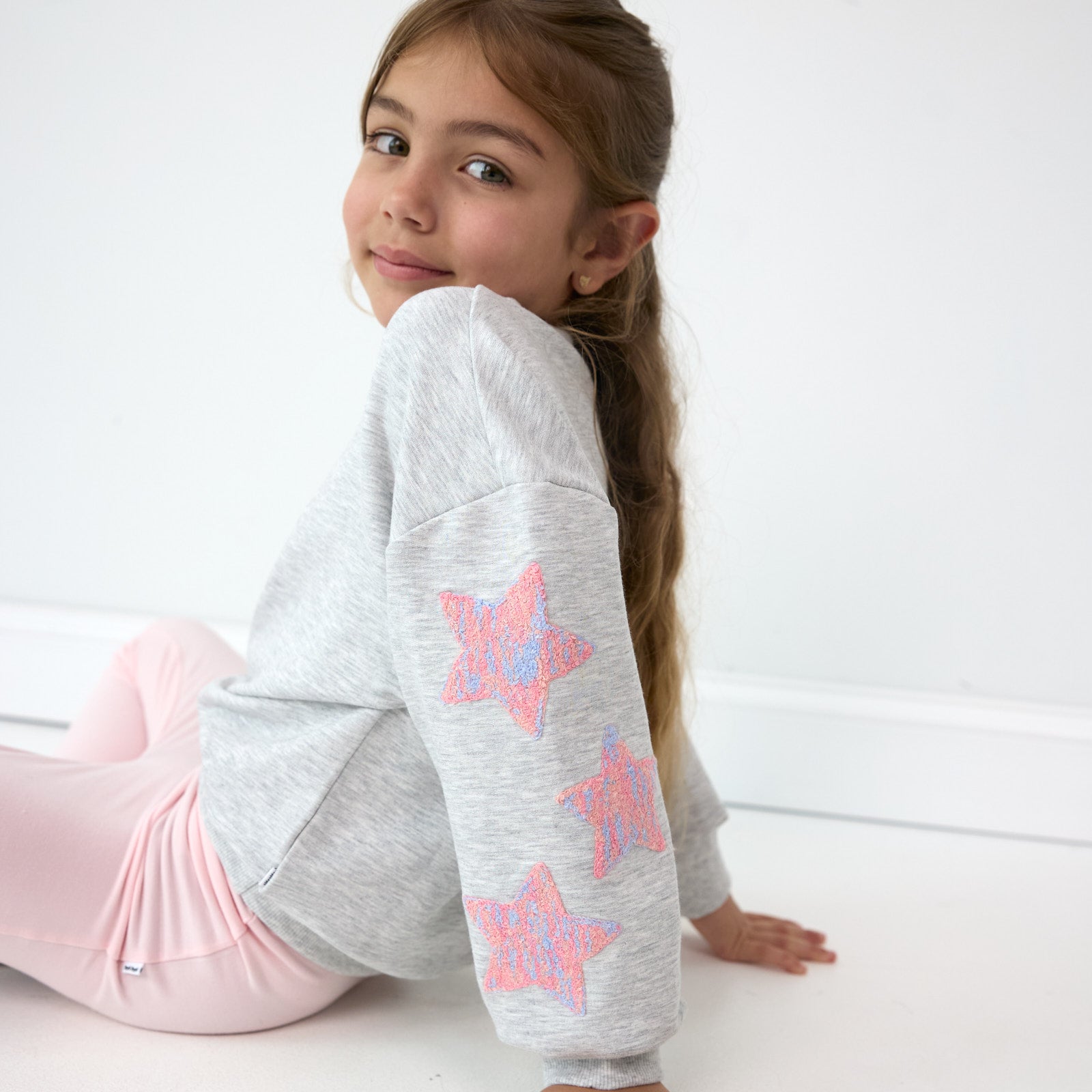 Girl posing while sitting down wearing the Light Heather Gray Drop Shoulder Crewneck and Prima Pink Leggings