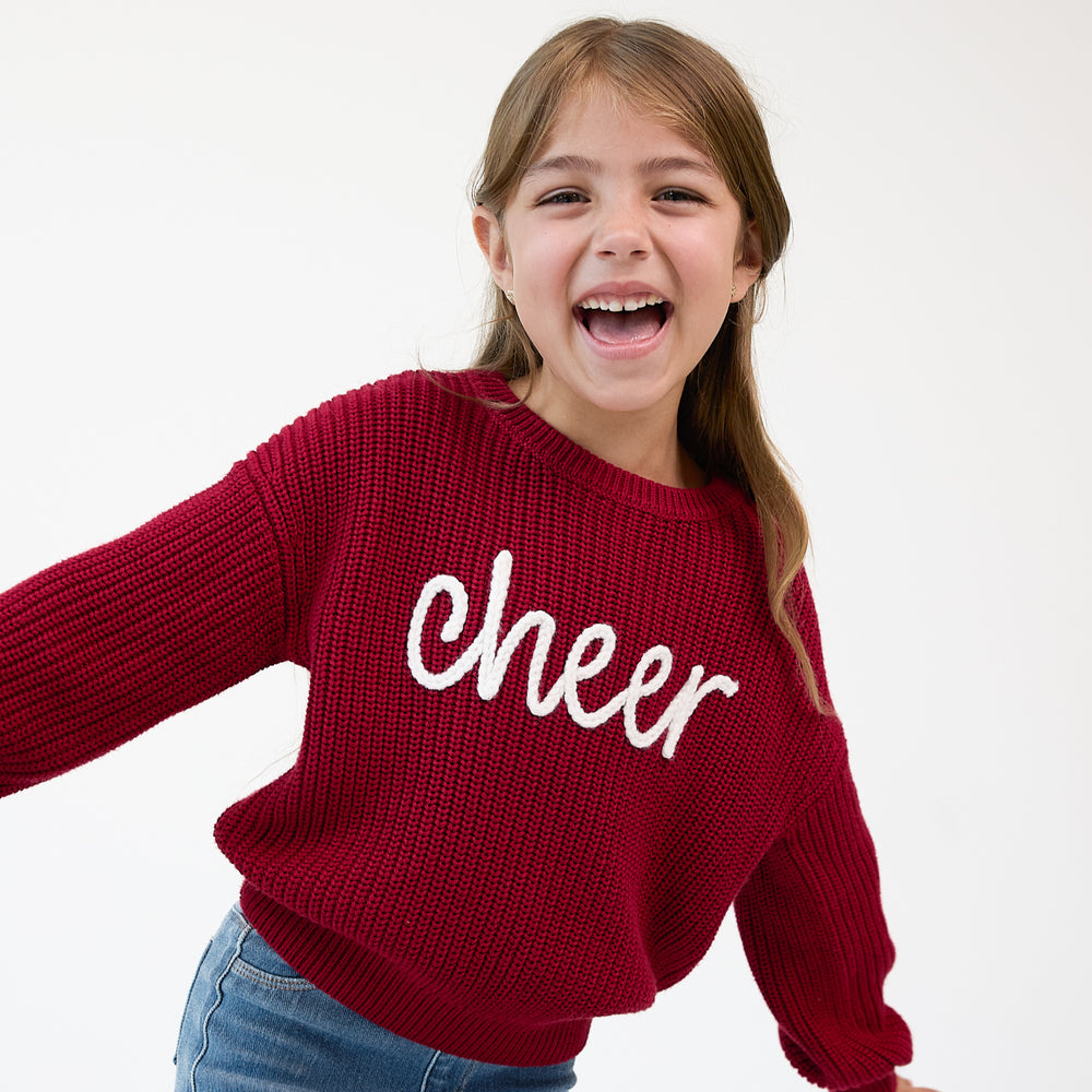 Close up image of a child wearing a Deep Crimson "Cheer" Drop Shoulder Crewneck