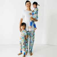 Dad with his two children wearing matching Party Pals pajamas. Dad is wearing men's Party Pals men's pants paired with a bright white men's top. Children are wearing Party Pals pjs in two piece and zippy styles.