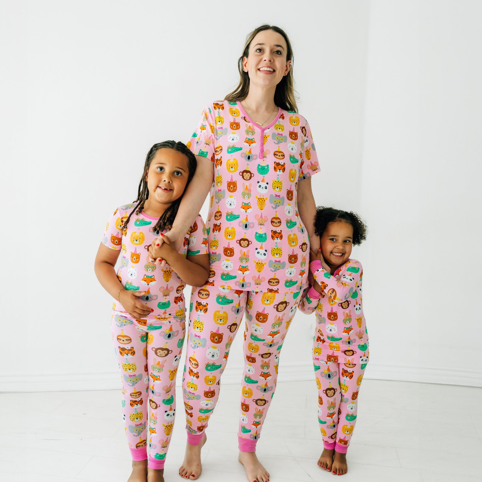 Mother and her two children wearing matching Pink Party Pals pjs. Mom is wearing women's Pink Party Pals women's pj top and matching women's pj pants. Children are wearing matching pj sets