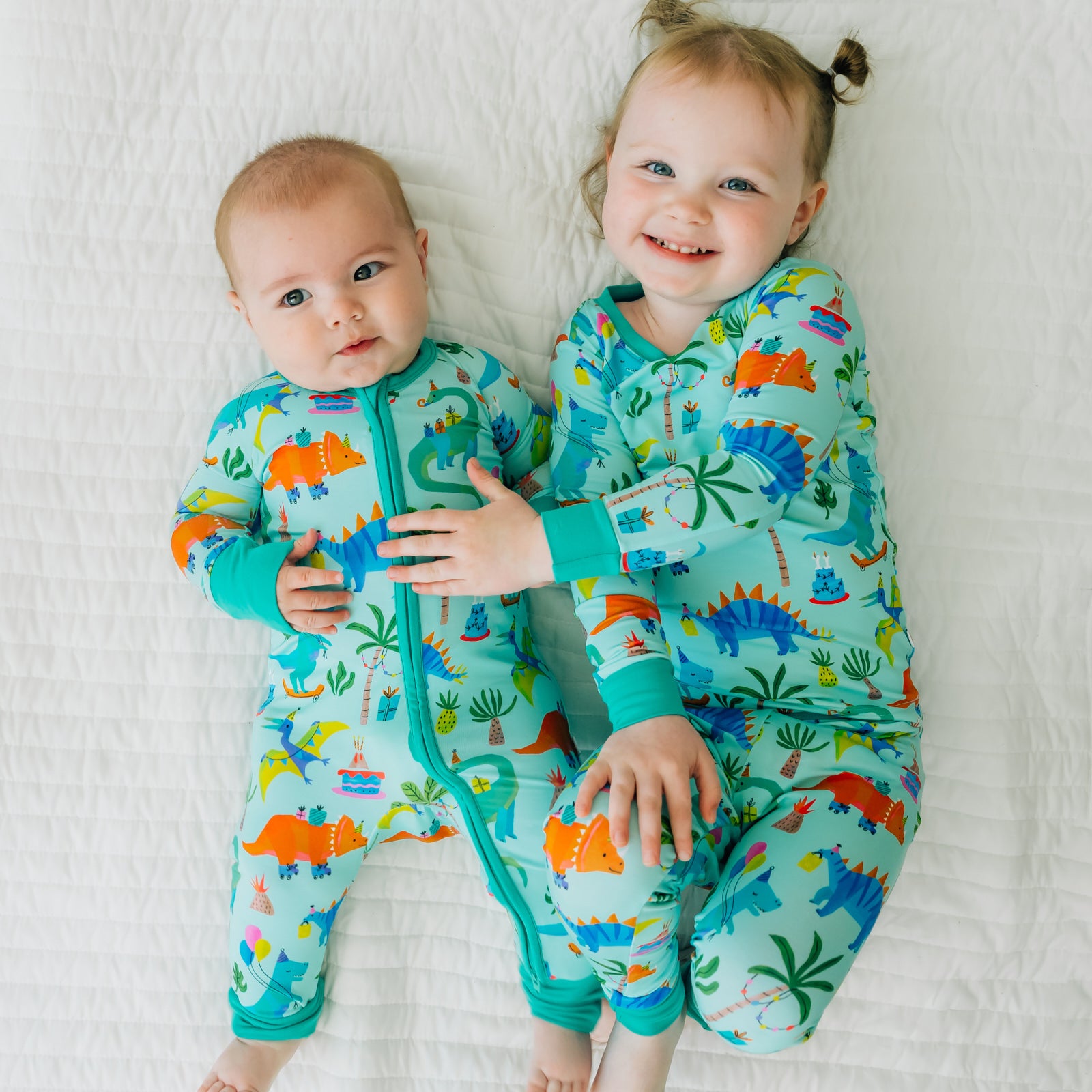 Two children cuddling wearing Prehistoric Party Pals in two piece and zippy styles