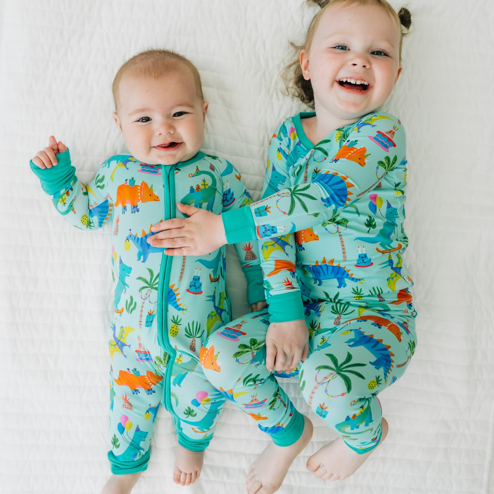 Two children cuddling wearing Prehistoric Party Pals in two piece and zippy styles