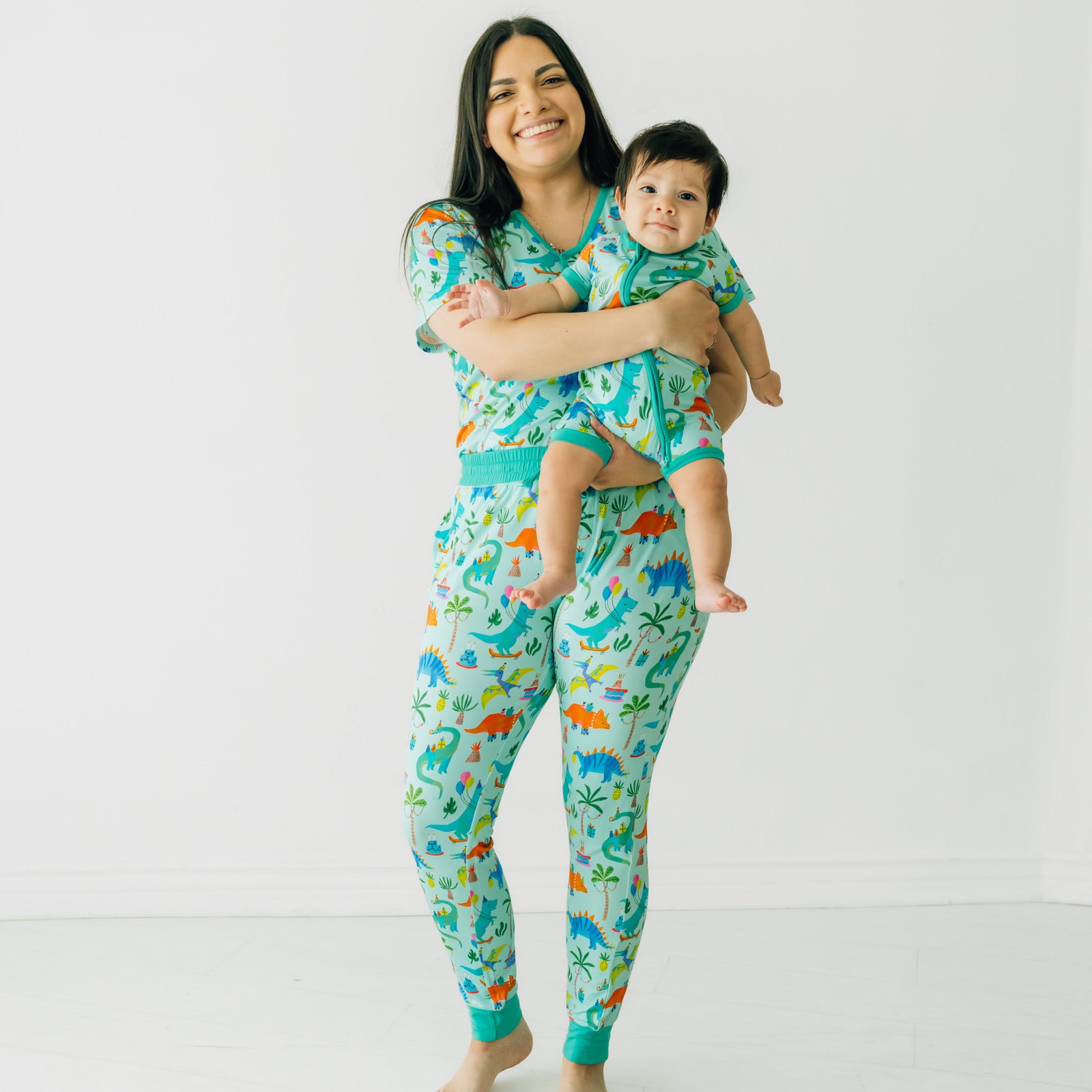 Woman with her child wearing Prehistoric Party women's pj pants and matching women's pj top. Her child is wearing a matching printed shorty zippy