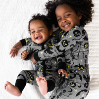 Baby on the left is in a Gray Glowing Ghouls Zippy & girl holding sibling is wearing the Gray Glowing Ghouls Two-piece Pajama Set