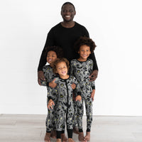 Male model in the Solid Black Men's Pajama Top and two boys are in the Gray Glowing Ghouls Two-piece Pajama Set. Boy in the middle is wearing the Gray Glowing Ghouls Zippy