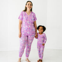 Mother and daughter holding hands wearing matching Magical Birthday pjs. Mom is wearing women's Magical Birthday pj top and matching pj pants. Child is wearing magical birthday two piece pj set