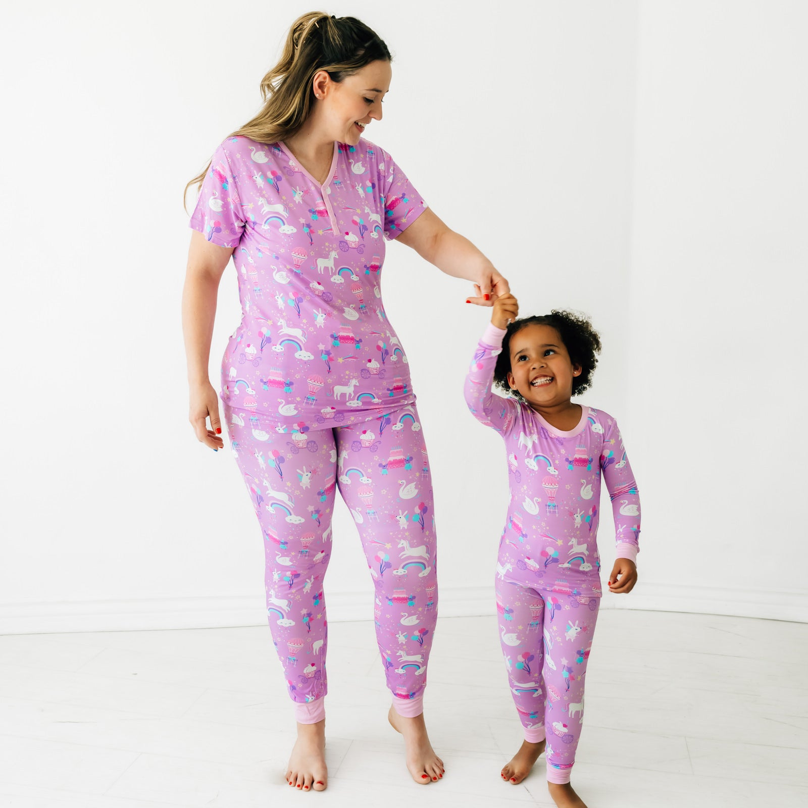 Mother and daughter dancing together wearing matching Magical Birthday pjs. Mom is wearing women's Magical Birthday pj top and matching pj pants. Child is wearing magical birthday two piece pj set