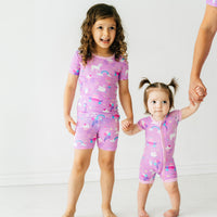 Two children holding hands wearing matching Magical Birthday pjs in short sleeve two piece and shorty zippy styles
