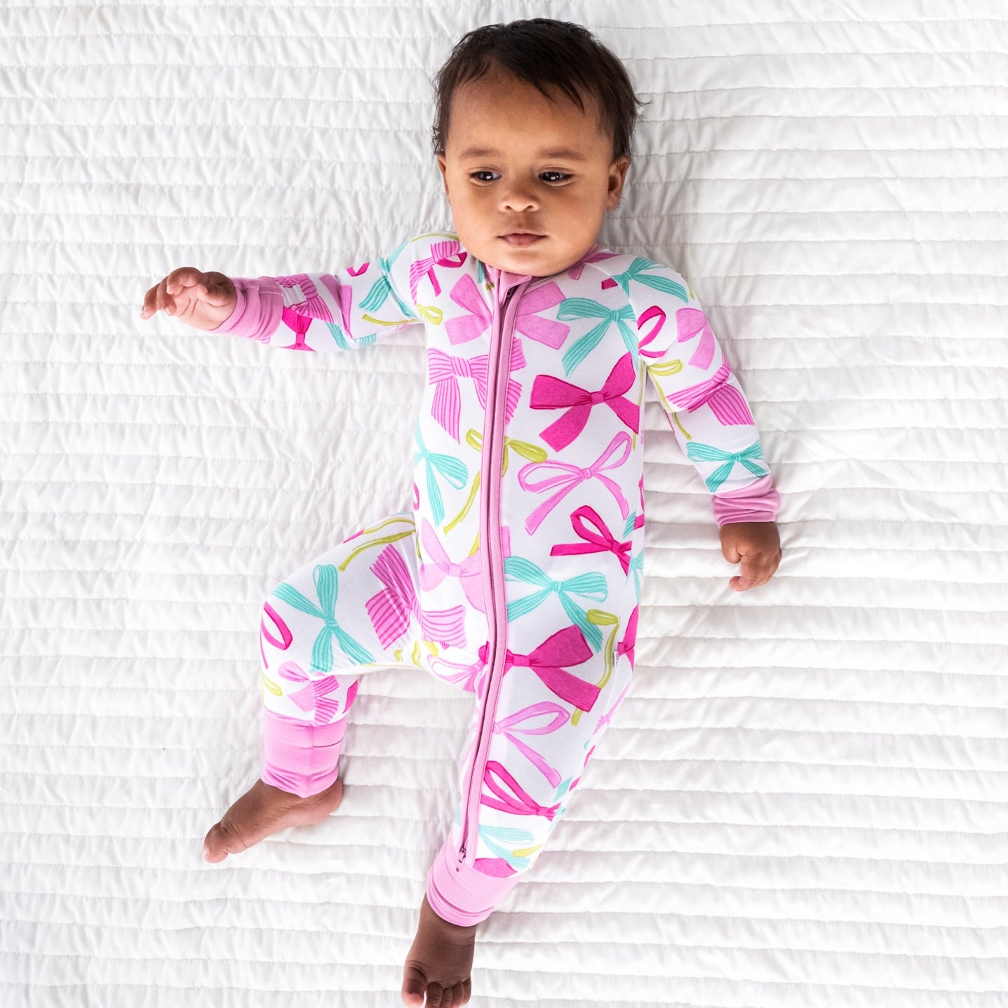 child laying on a bed wearing a Ribbons and Bows zippy