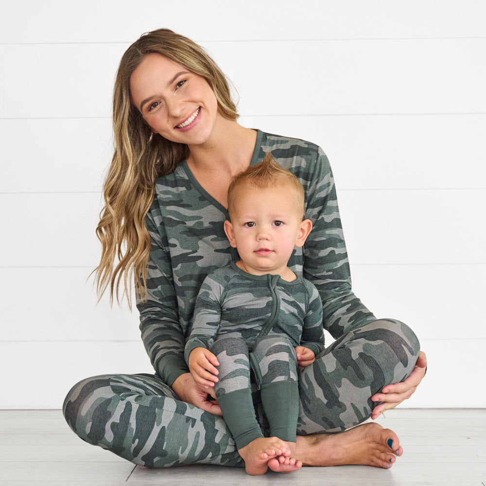 Female model wearing the Vintage Camo Women's Pajama Pants & Top, while holding baby in the Vintage Camo Zippy