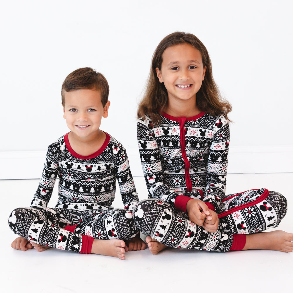 two children sitting wearing Mickey Fair Isle pjs in zippy and two piece pj sets