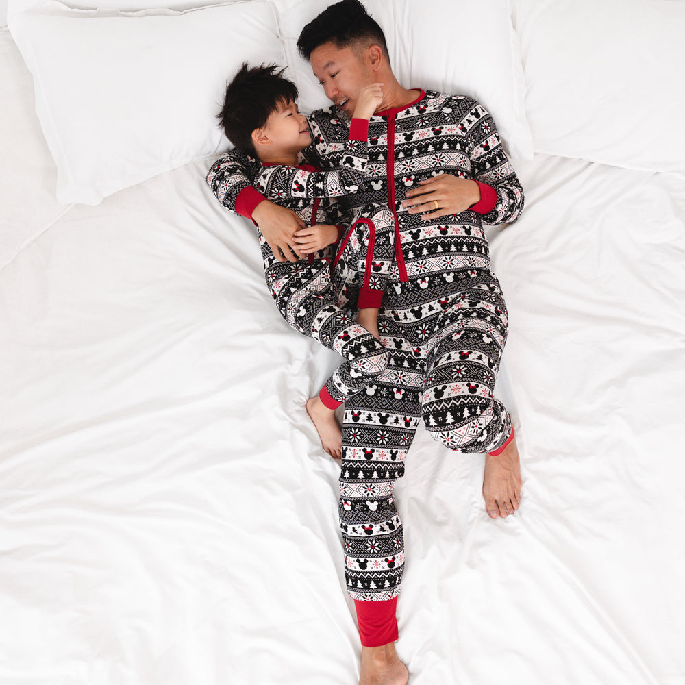 Man laying on a bed cuddling his child wearing matching zippies in men's and children's styles