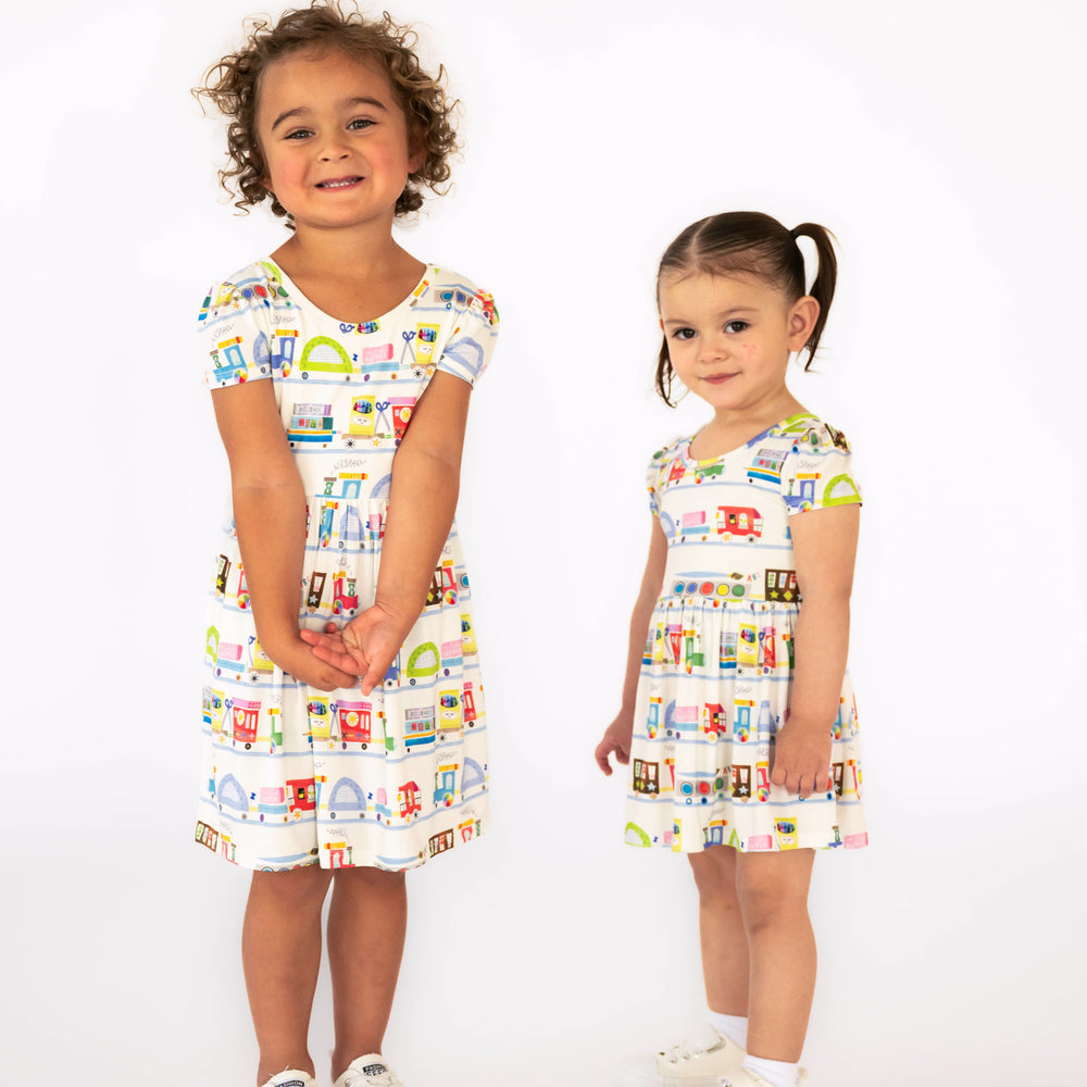 Children standing while wearing the Education Express Skater Dress and  Education Express Skater Dress with Bodysuit