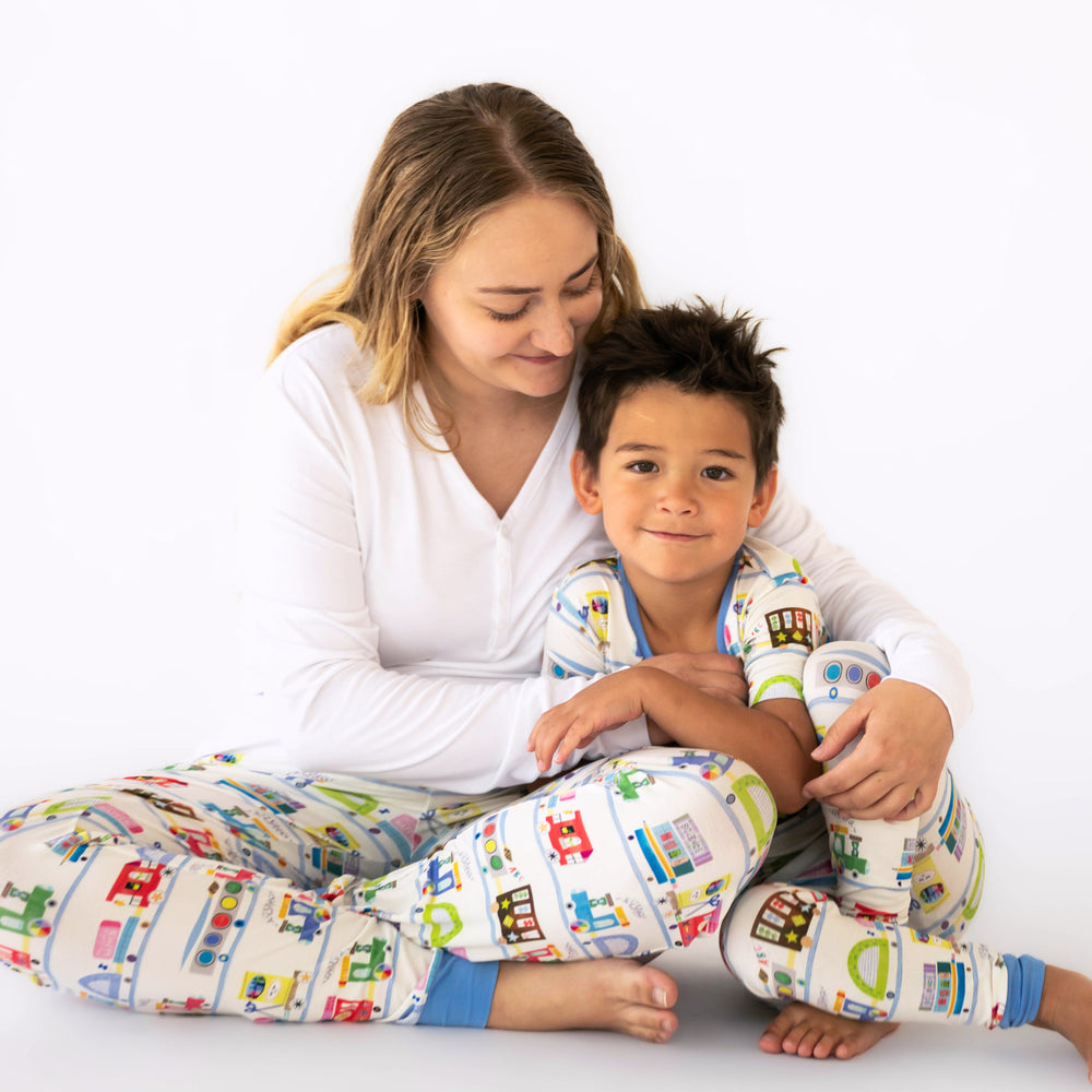 Mother and child cuddling. Mom is wearing a women's bright white pj top paired with Education Express printed women's pj pants. Child is matching wearing Education Express two piece pj set.