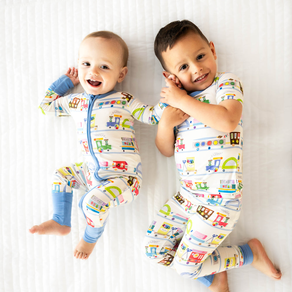 Children laying down while wearing the Education Express Two-Piece Short Sleeve Pajama Set and Education Express Zippy