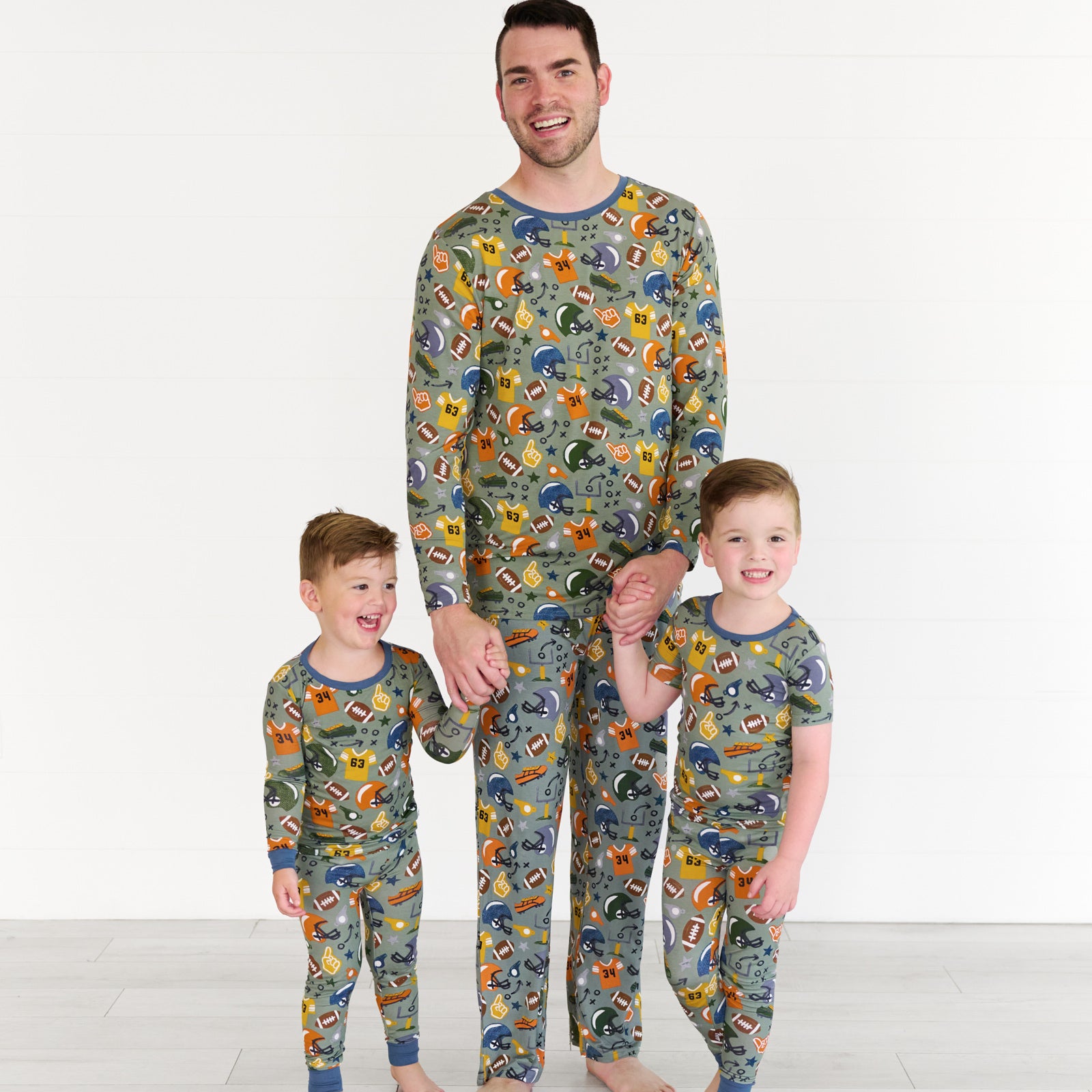 Boy on the left is wearing the touchdown-time-two-piece-pajama-set, the father in the middle is wearing the touchdown-time-mens-pajama- top & pants. The boy on the right is the touchdown-time-two-piece-short-sleeve-pajama-set