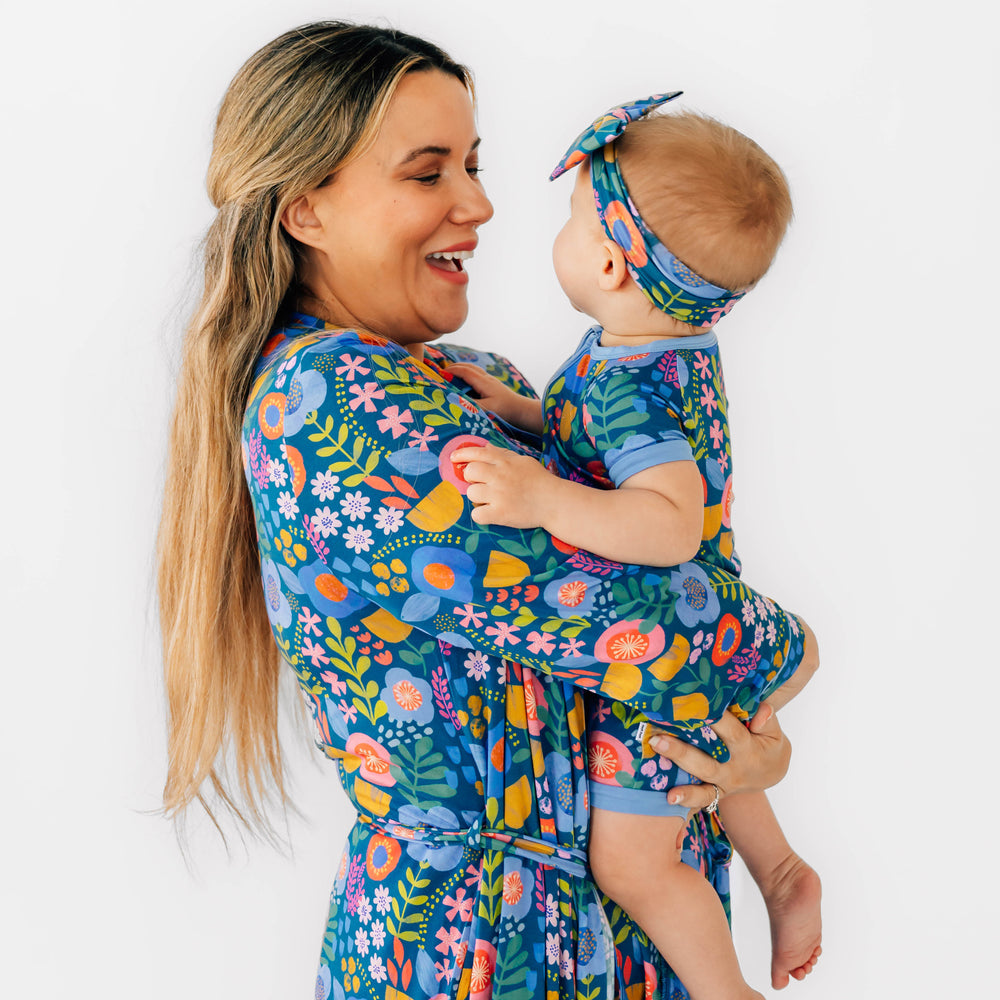 Mother and daughter wearing the Folk Floral print. Girl is wearing the Folk Floral Luxe Bow Headband and the Shorty Zippy in Folk Floral and Mother is smiling while wearing the Folk Floral Woman's Robe