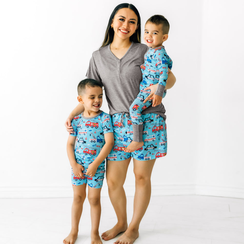 Mom and her two children wearing matching To The Rescue printed pajamas. Mom is wearing women's To the Rescue pj shorts and coordinating heather gray women's pajama top. Children are wearing To The Rescue two piece pajama sets