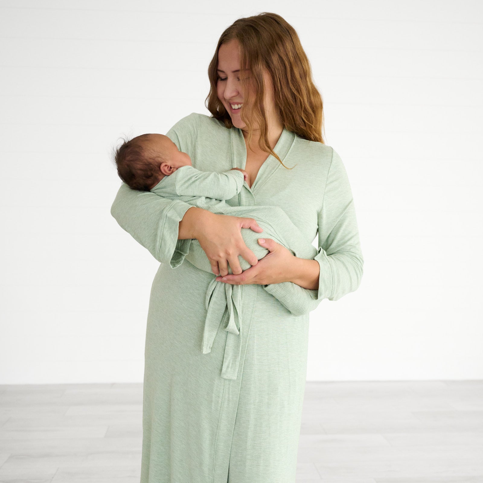 Woman cradling her child wearing a Heather Sage women's robe and her child is wearing a heather Sage Ribbed infant gown