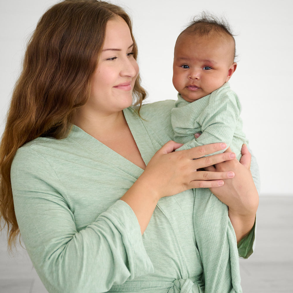 Mother wearing a Heather Sage women's robe holding her child wearing a matching Heather Sage infant gown