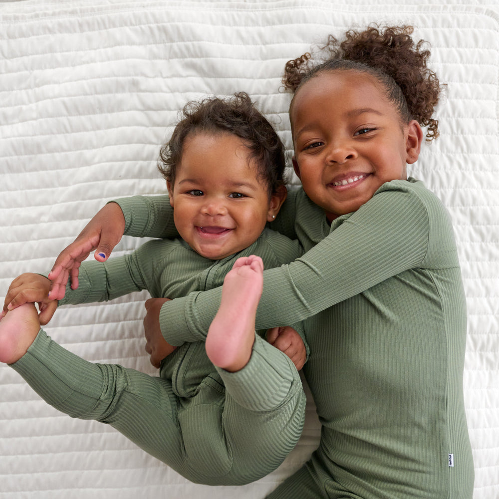 Baby on the left is wearing the Moss Ribbed Zippy and girl on the right is the Moss Ribbed Two-piece Pajama Set