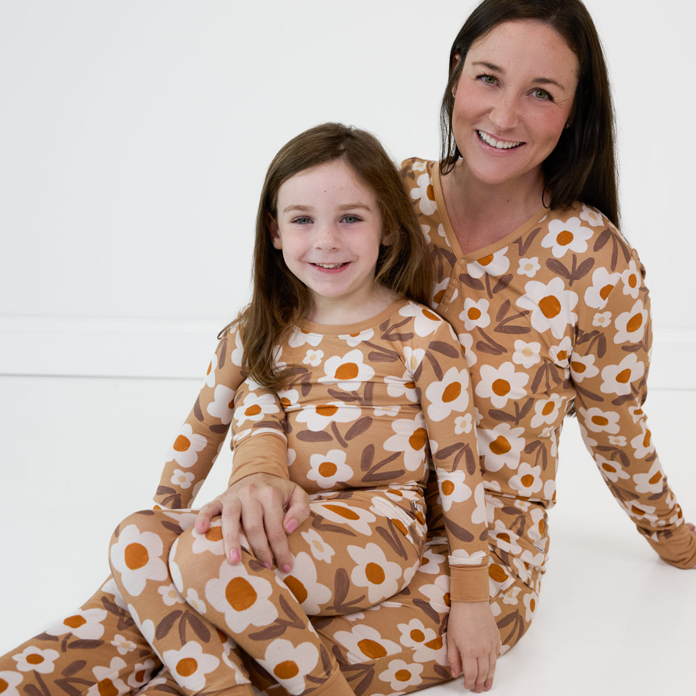 Image of a mother and daughter sitting together wearing matching Daisy Daydream pajamas in a women's  pajama top and bottom and kid's two piece styles