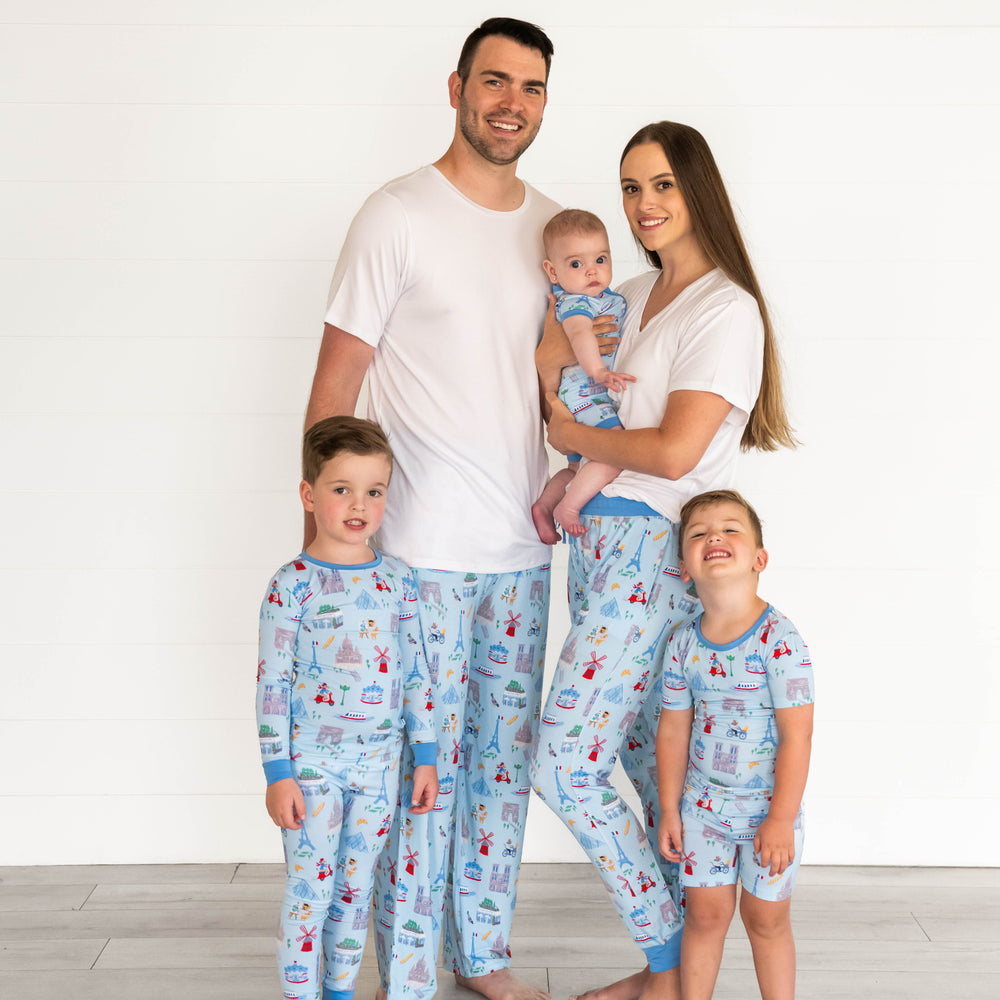 Boy on the right is wearing the Blue Weekend in Paris Two-Piece Pajama Set and father is wearing the Blue Weekend in Paris Men's Pajama Pants. Baby in the middle is wearing the Blue Weekend in Paris Shorty Zippy and mother holding the baby is in the Blue Weekend in Paris Women's Pajama Pants. Boy on the left is in the Blue Weekend in Paris Short-sleeve Two-Piece Pajama Set