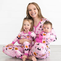 Girl on the left is in the Pink Glowing Ghouls Two-piece Pajama Set. Mother is in the Pink Glowing Ghouls Women's Pajama Pants and Top and baby is wearing the Pink Glowing Ghouls Zippy