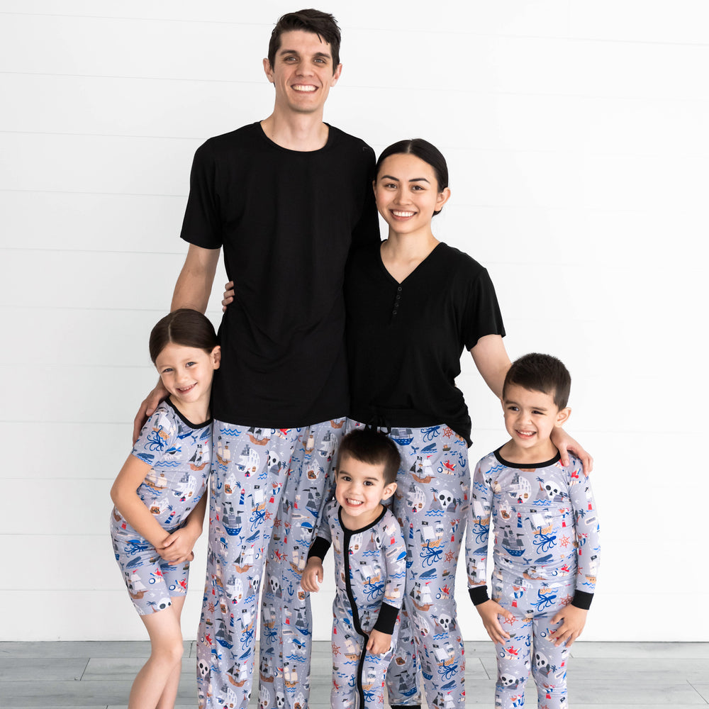 Family of five is wearing the Pirate's Map Collection. Girl on the left is wearing the Pirate's Map Two-Piece Short Sleeve & Shorts Pajama Set. Father is wearing the Pirate's Map Men's Pajama Pants and Black Men's Short-sleeve Top.The boy in the middle is wearing the Pirate's Map Zippy and the mother is wearing the Black Women's Short-sleeve Top and Pirate's Map Women's Pajama Pants. The boy on the right is wearing the Pirate's Map Pajama Set.