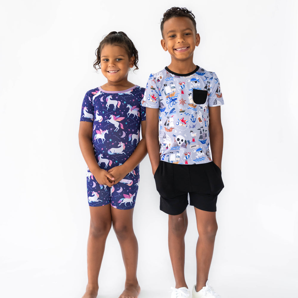 Girl on the left is wearing the Shorts PJ Set and boy on the right is wearing the Pirate's Map Pocket Tee and Black Play Shorts 