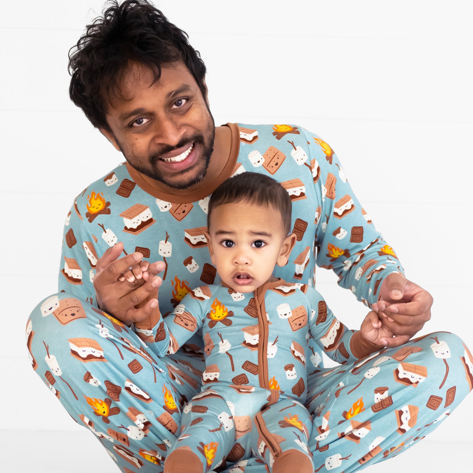 father and child wearing matching S'mores Galore pjs. Dad is wearing men's S'mores Galore pj top and matching men's pj pants, his child is wearing a matching zippy