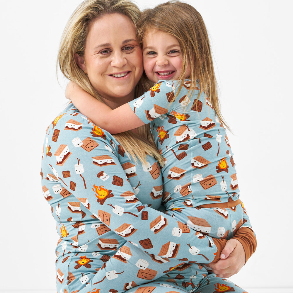 woman holding her child wearing matching S'mores Galore pjs. Mom is wearing a women's S'mores Galore pj top and her daughter is wearing a matching two piece pj sets